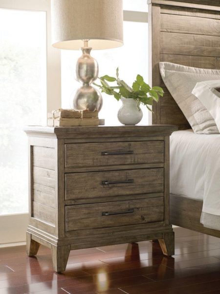 Wooded nightstand with bedroom accessories such as a plan. books and a lamp.